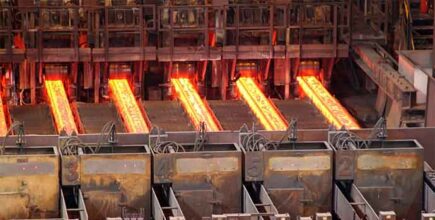 Glowing hot steel slabs on rollers inside an industrial steel mill, showcasing metal production process.