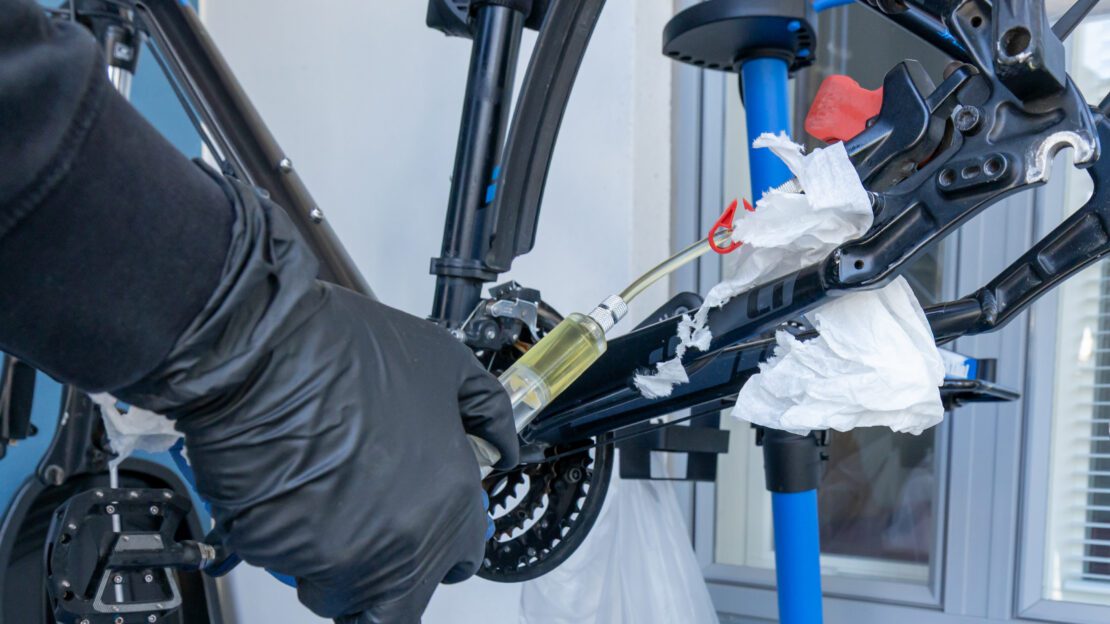 A person is bleeding a disc brake system before flushing